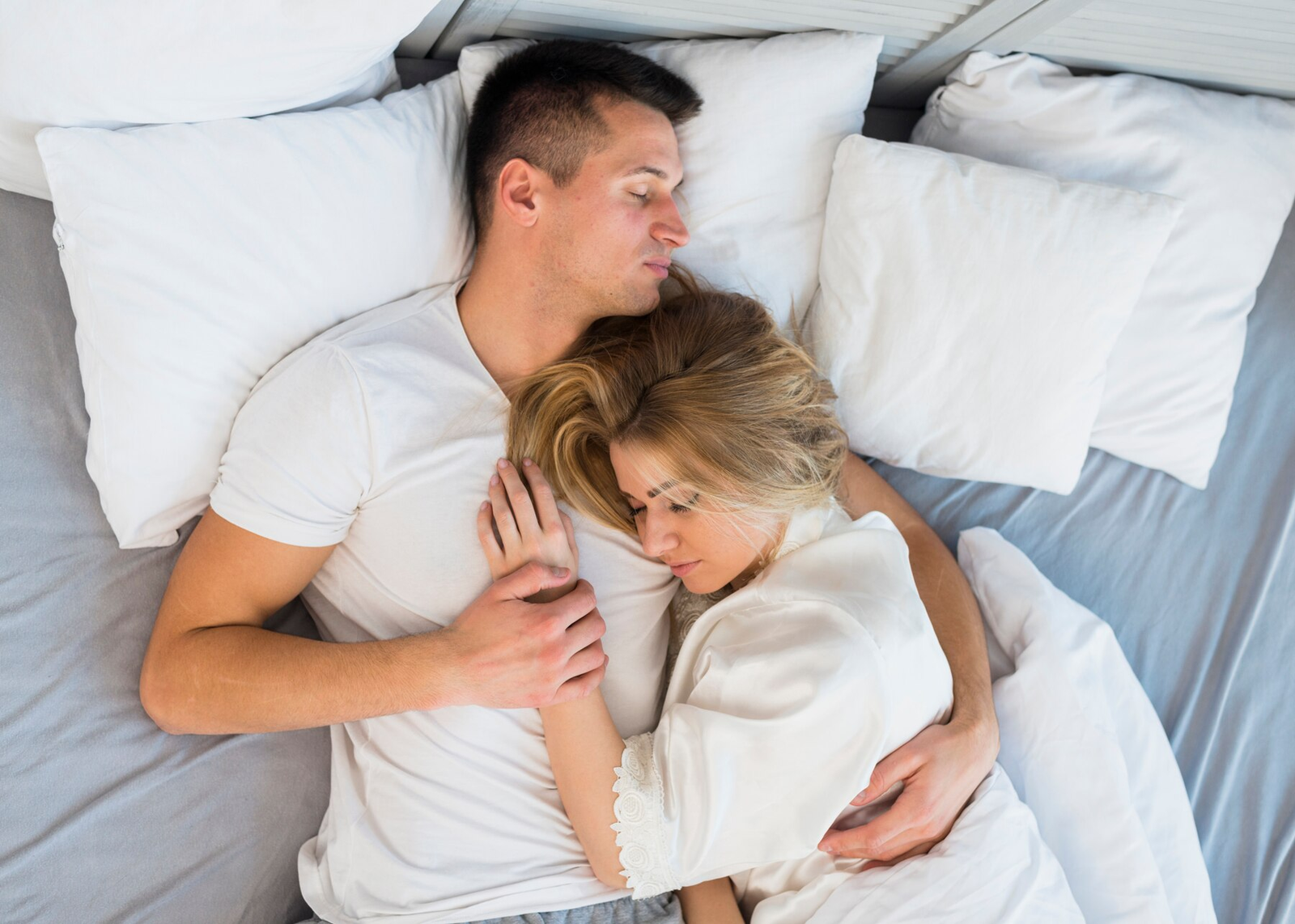 A couple sleeping in white bedding